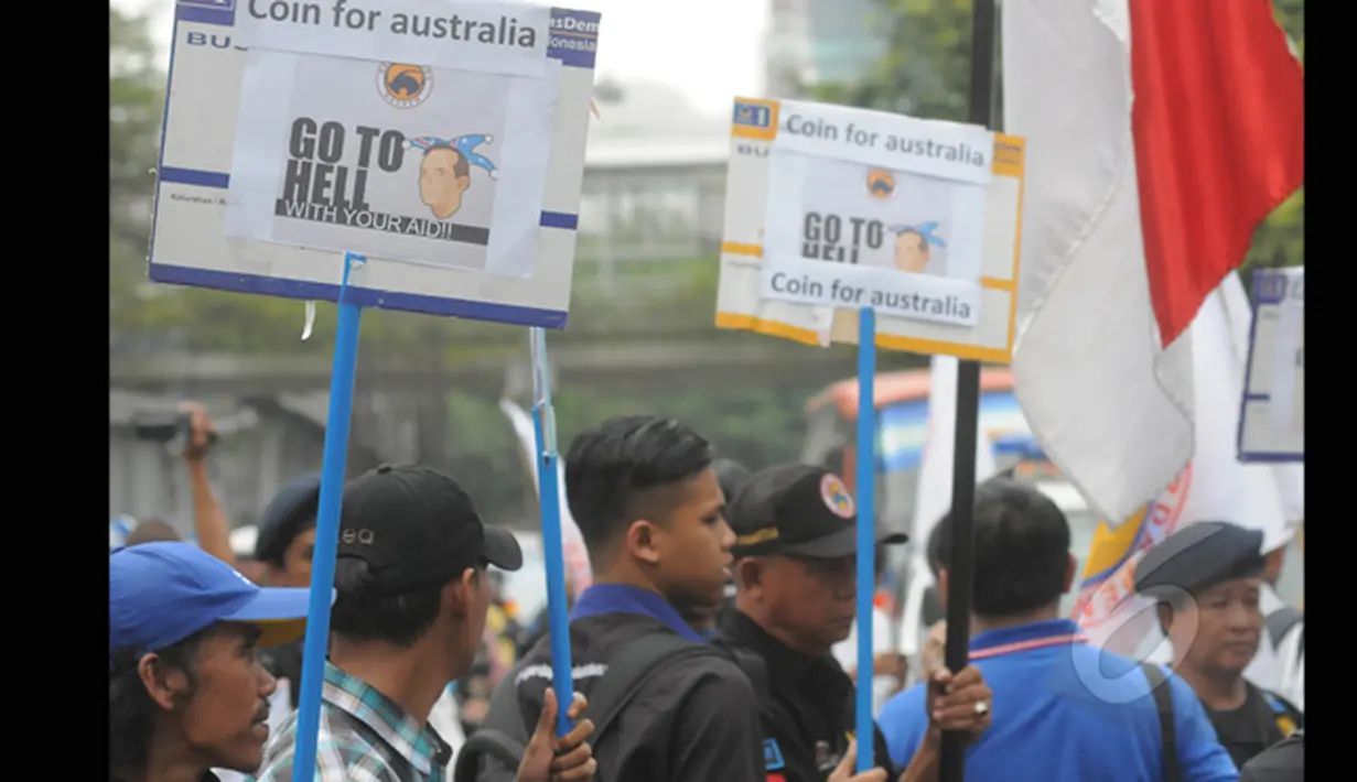 Anggota Garda Pemuda Nasdem membawa poster bergambar Tonny Abbott saat menyerahkan ribuan koin untuk PM Tony Abbot di depan kantor Kedutaan Besar Australia, Jakarta, Jumat (27/2/2015). (Liputan6.com/Herman Zakharia)