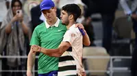 Pemenang Carlos Alcaraz (kanan) dari Spanyol menyemangati Jannik Sinner dari Italia di akhir pertandingan final tunggal putra pada hari ke-15 turnamen tenis Prancis Terbuka di Lapangan Philippe-Chatrier di Kompleks Roland-Garros di Paris pada 8 Juni 2025. (JULIEN DE ROSA/AFP)