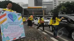 Aksi damai tersebut dengan membagikan bunga dan brosur mengenai kanker kepada pengendara yang lewat di Jalan Bundaran Tugu Tani dan Bundaran Senayan, Jakarta, Rabu (4/2/2015). (Liputan6.com/Herman Zakharia)