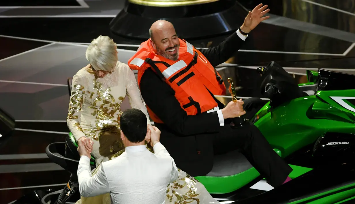 Pembawa acara Jimmy Kimmel membantu turun Helen Mirren dari jet ski yang menjadi hadiah untuk Mark Bridges saat acara Academy Awards ke-90 di Hollywood, California (4/3). (Kevin Winter / Getty Images / AFP)