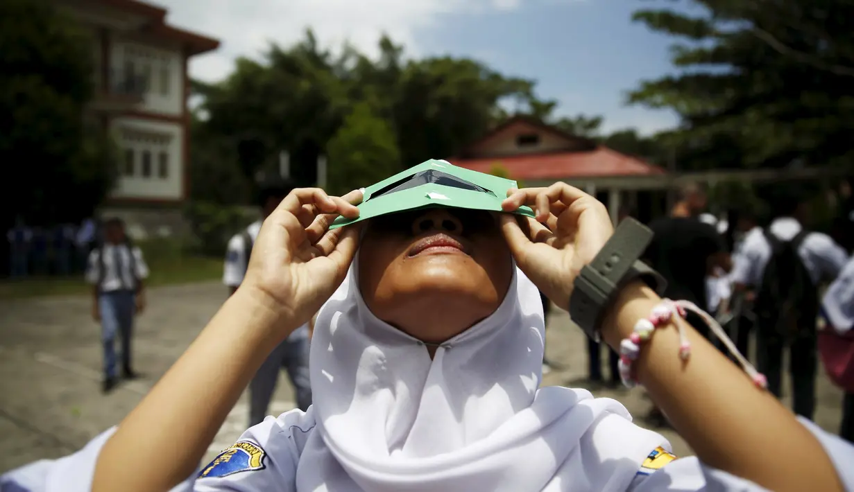 Siswi mencoba melihat matahari dengan kacamata filter buatan sendiri saat workshop bersama Hong Kong Astronomical Society dan LAPAN di sekolah di Ternate, (7/3). Kacamata ini akan digunakan untuk mengamati Gerhana Matahari Total. (REUTERS/Beawiharta)