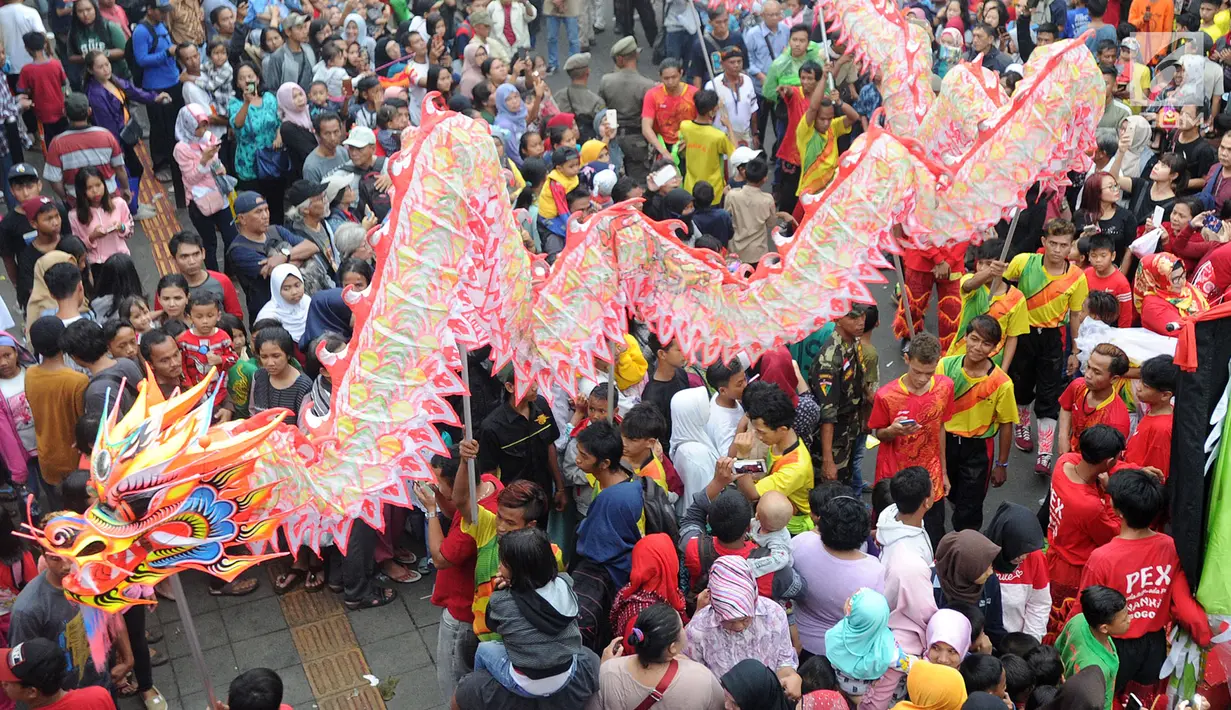 Warga memadati jalan raya saat arak-arakan atraksi liong perayaan Cap Go Meh melewati Jalan Suryakencana, Bogor, Jawa Barat, Selasa (19/2). Selain liong, perayaan ini juga dimeriahkan dengan serangkaian acara seni dan budaya. (Merdeka.com/Arie Basuki)