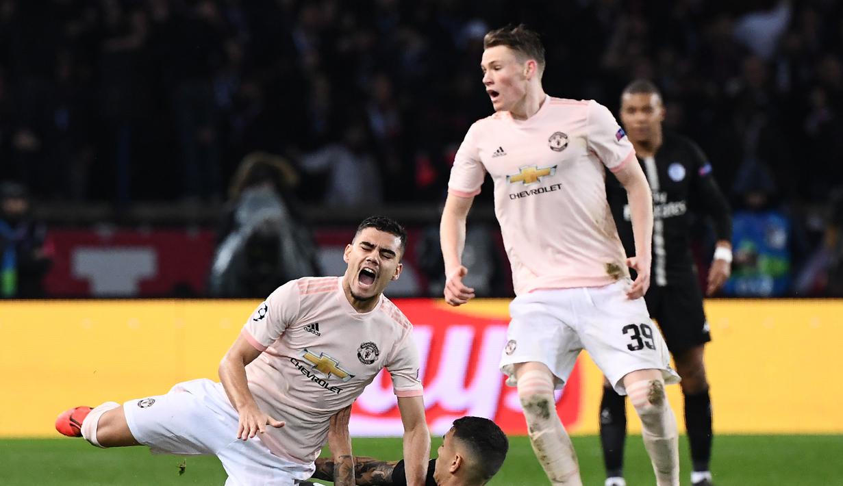 Andres Pereira dijatuhkan oleh Leandro Peredes pada leg kedua, babak 16 besar Liga Champions yang berlangsung di Stadion Parc des Princes, Paris, Kamis (7/3). Man United menang 3-1 atas PSG. (AFP/ Anne-Christine Poujoulat)
