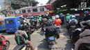 Pengendara menanti di pintu perlintasan kereta sebidang di Jalan KH Mas Mansyur, Jakarta, Senin (30/10). Perlintasan sebidang ini rencananya segera ditutup karena dianggap menjadi salah satu titik kemacetan di Jakarta Pusat. (Liputan6.com/Angga Yuniar)