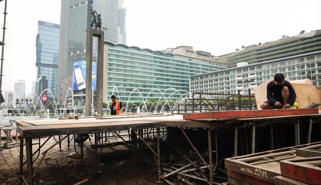 Pekerja memasang panggung untuk acara malam tahun baru di sekitar kawasan Bundaran HI, Jakarta, Rabu (25/12/2019). Merayakan pergantian tahun, Pemprov DKI Jakarta menggelar sejumlah acara di sejumlah titik sepanjang Jalan Sudirman-MH Thamrin. (Liputan6.com/Faizal Fanani)