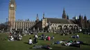 Sejumlah orang bersantai di bawah sinar matahari di Parliament Square di pusat kota London Inggris, Sabtu (8/4). (AFP PHOTO / Daniel Leal-Olivas)
