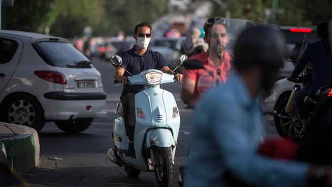 Seorang pria dengan masker mengendarai motor di sebuah jalan di Teheran, 28 Juni 2020. Presiden Iran Hassan Rouhani pada Minggu (28/6) mengatakan mengenakan masker di tempat umum akan menjadi wajib mulai pekan depan di tengah meningkatnya kasus dan kematian akibat COVID-19. (Xinhua/Ahmad Halabisaz)