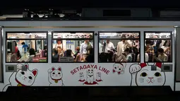 Gambar pada 25 Juni 2019, penumpang menaiki kereta Setagaya Line bergambar kucing putih dengan tangan melambai-lambai yang disebut maneki-neko di dekat Kuil Gotokuji, Tokyo. Setiap hari, kuil Gotokuji ramai dikunjungi turis yang meminta keberkahan dan kemujuran dalam hidupnya. (AP/Jae C. Hong)