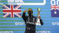 Pembalap Mercedes Lewis Hamilton memegang trofi setelah memenangkan F1 GP Eifel di Nuerburgring, Nuerburg, Jerman, Minggu (11/10/2020). Hamilton dengan 91 kemenangannya menyamai legenda F1 Michael Schumacher. (Wolfgang Rattay, Pool via AP)