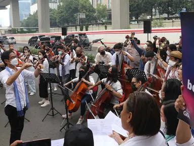 Komposer Addie MS memimpin penampilan orkestra saat aksi seruan damai di depan Kedutaan Besar Federasi Rusia, Jakarta, Rabu (30/3/2022). Aksi tersebut mengangkat tema "Setangkai Kembang dan Satu Nyanyian" dengan membawakan lagu Rayuan Pulau Kelapa versi bahasa Rusia. (Liputan6.com/Herman Zakharia)