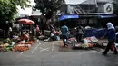Pedagang berjualan dekat tanda ‘X‘ yang digunakan sebagai pembatas physical distancing di Pasar Perumnas Klender, Jakarta, Kamis (18/6/2020). Selain sistem ganjil genap kios, pengelola pasar menerapkan physical distancing antarlapak untuk mencegah penularan COVID-19. (merdeka.com/Iqbal S. Nugroho)