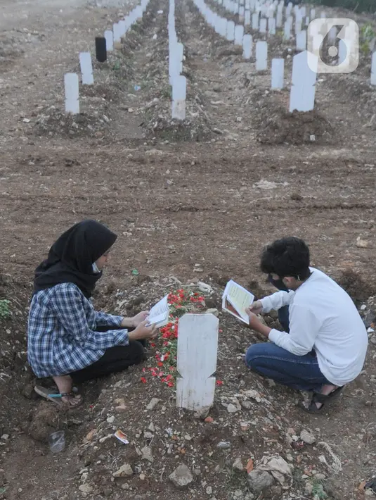 Keluarga berdoa depan pusara makam korban Covid-19 di TPU Srengseng Sawah 2, Jakarta Selatan, Jumat (19/3/2021). Seminggu terakhir intensitas pemakaman korban Covid-19 menurun drastis sebesar rata-rata 20 jenazah/minggu dibandingkan sebelumnya rata-rata 35 jenazah/minggu. (merdeka.com/Arie Basuki)