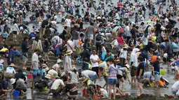 Sejumlah pengunjung menggali pasir untuk berburu kerang di pantai kawasan Yokohama, dekat Tokyo, Senin (30/4). Puluhan ribu orang berdesakan di pantai selama Golden Week atau periode liburan di Jepang pada akhir April hingga awal Mei. (AP/Koji Sasahara)