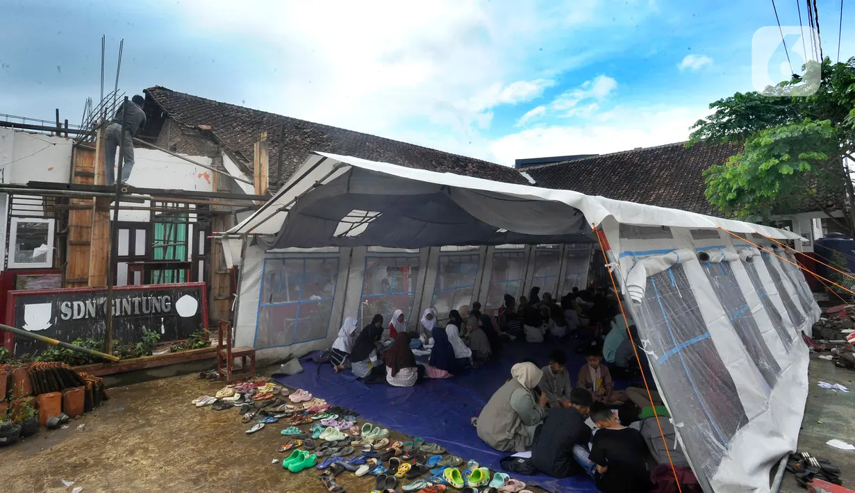 Murid-murid korban gempa belajar pada tenda darurat yang dibangun di halaman sekolah di SDN Gintung, Mangunkerta, Cianjur, Jumat (23/12/2022). Lebih dari sebulan sejak musibah gempa bumi 5,2 SR sejumlah murid sekolah di Cianjur masih belajar pada tenda darurat. (merdeka.com/Arie Basuki)