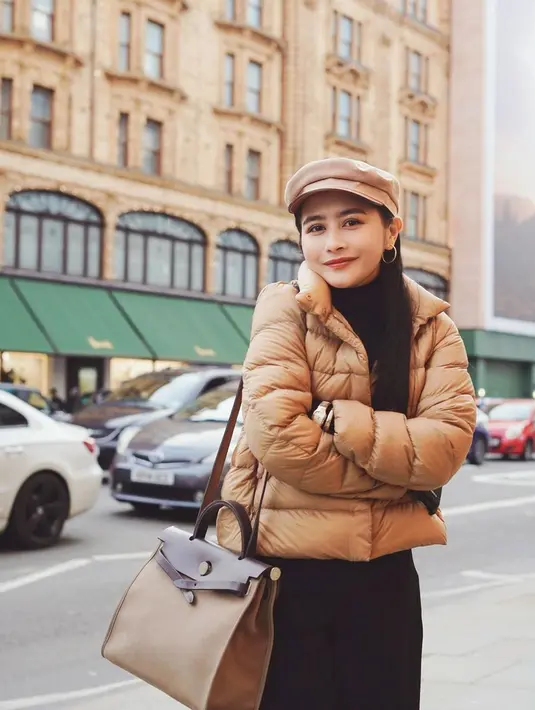 Prilly Latuconsina juga sedang berada di London. Di sini, Prilly terlihat mengenakan outfit musim dingin; turtleneck hitam ditumpuknya dengan puffer jacket cokelat, dipadu celana panjang hitam, tas, dan topi berwarna cokelat yang serasi. [Foto: Instagram/prillylatuconsina96]