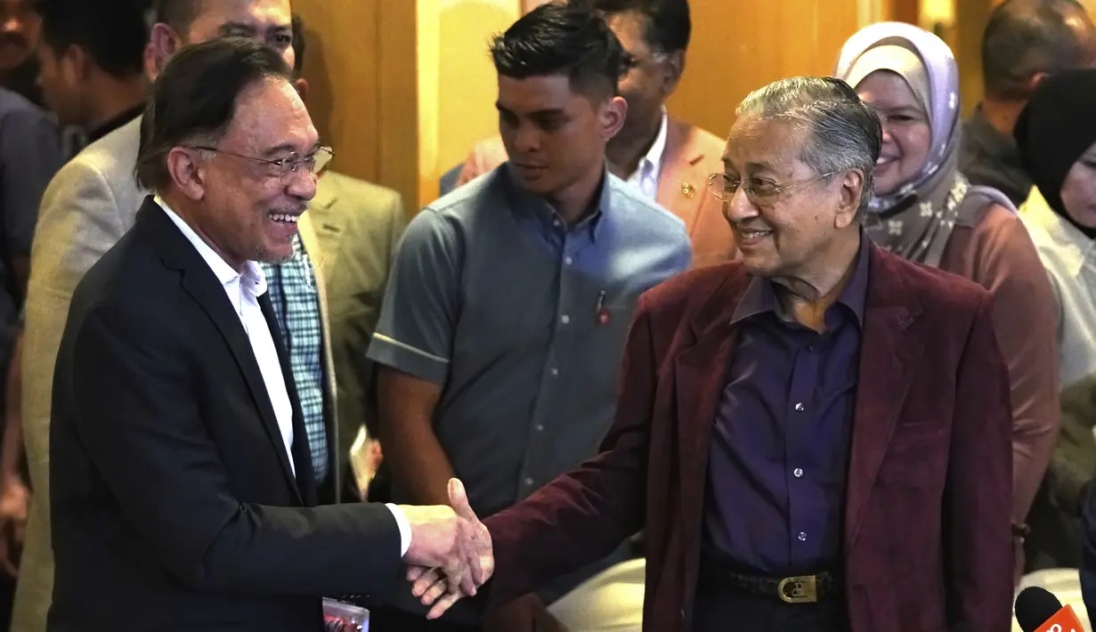 Perdana Menteri Malaysia Mahathir Mohamad (kanan) berjabat tangan dengan Anwar Ibrahim di Putrajaya, Malaysia, Sabtu (22/2/2020). Sebelumnya, Mahathir telah berjanji akan menyerahkan jabatannya kepada Anwar Ibrahim. (AP Photo/Vincent Thian)