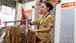 Pegawai merapikan kain batik yang dipajang pada acara Relaunching Batik Keris Online di Bekraf Habibie Festival 2017 Jakarta. Batik Keris mulai merambah ke Online hadir dengan tampilan dan fitur yang terbaru. (Liputan6.com/Pool)