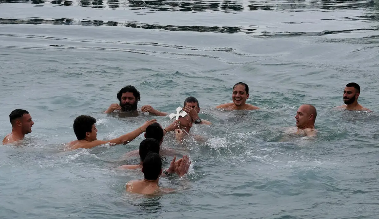 Seorang peziarah mencium salib setelah dilemparkan oleh pendeta Ortodoks ke dalam air saat upacara Epiphany di Ayia Napa, Siprus, 6 Januari 2022. Epiphany adalah sebuah hari raya keagamaan dalam sejumlah denominasi gereja Kristen pada tanggal 6 Januari. (AP Photo/Petros Karadjias)
