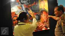 Pelukis Cak Kandar (kiri) menerangkan makna dari lukisan yang dipajang di Pameran Lukisan Dua Tanda di Hotel Sultan Jakarta, Senin (21/3/2016). Badrodin Haiti menyambut baik keberadaan Pameran Lukisan Dua Tanda. (Liputan6.com/Faisal R Syam)