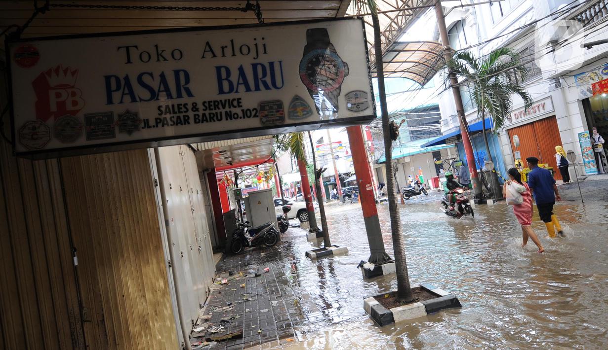 Warga melintas di kawasan pertokoan Pasar Baru, Jakarta, Kamis (2/1/2020). Pasca banjir yang melanda sejumlah titik di Jakarta pada Rabu (1/1), aktivitas perniagaan di kawasan Pasar Baru masih terlihat sepi dan sebagian toko masih tutup. (Liputan6.com/Helmi Fithriansyah)