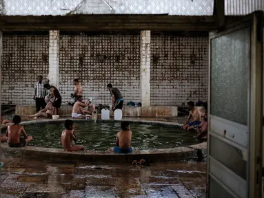 Pengunjung menikmati kolam renang air hangat dari belerang di Hamam Alli, Mosul, Irak, (27/4). Sebelum ISIS mengambil alih Hamam Alil pada 2014, warga Irak selalu mengunjungi spa bersejarah di selatan Mosul ini. (AP Photo/Bram Janssen)