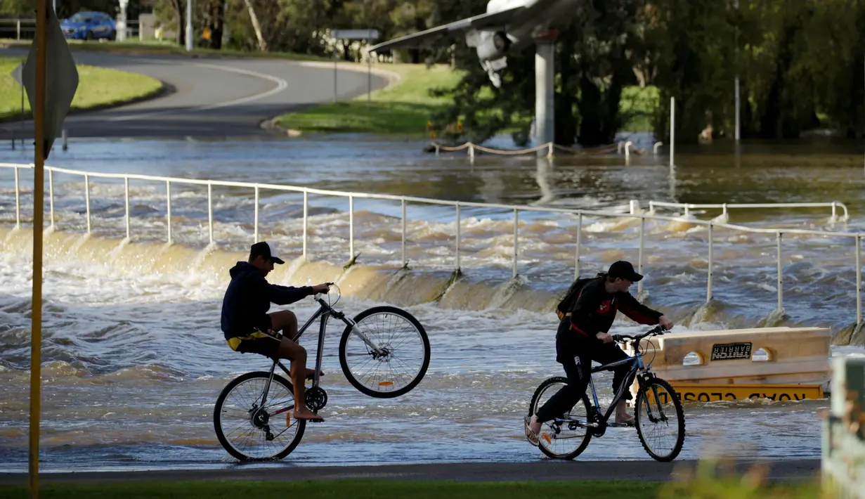 Dua remaja melihat banjir yang melanda Kota Forbes di New South Wales, Australia, Selasa (27/9). Sekitar 1.000 warga memilih mengungsi karena Sungai Lachlan tak sanggup menampung curah hujan sehingga menyebabkan banjir. (REUTERS / Jason Reed)