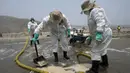 Petugas kebersihan bekerja untuk mengeluarkan minyak dari Pantai Cavero di Callao, Peru, 26 Januari 2022. Pembersihan Pantai Cavero dari tumpahan minyak kapal tanker Mare Doricum yang dihantam gelombang akibat letusan gunung berapi Tonga masih terus dilakukan. (Cris BOURONCLE/AFP)