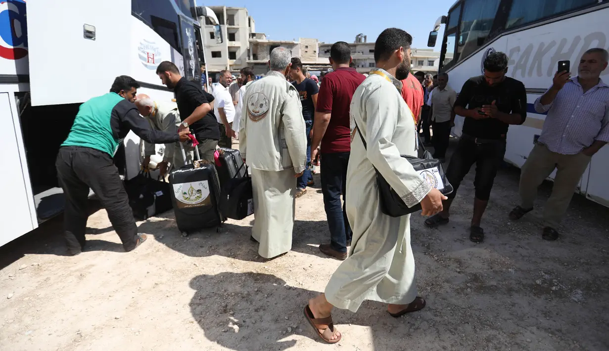 Warga Suriah dari provinsi Idlib, berkumpul sebelum menaiki bus ke Tanah Suci Makkah di kota Binnish, Senin (22/7/2019). Jemaah calon haji asal Suriah melakukan perjalanan ke Arab Saudi untuk menjalankan ibadah haji dari perbatasan Bab al-Hawa yang berseberangan dengan Turki. (Omar HAJ KADOUR/AFP)