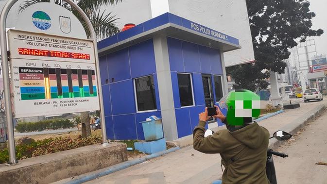 Seorang warga Pekanbaru mengabadikan ISPU yang menyatakan udara sangat tidak sehat karena kabut asap. (Liputan6.com/M Syukur)