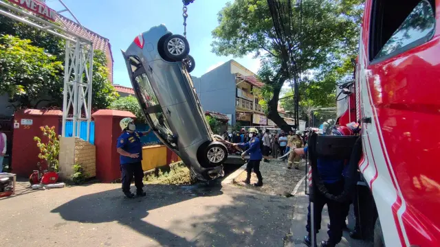 Petugas Damkar mengevakuasi mobil yang terpersok ke selokan di Jalan Pembaharuan, Kelapa Dua Wetan, Ciracas, Jakarta Timur