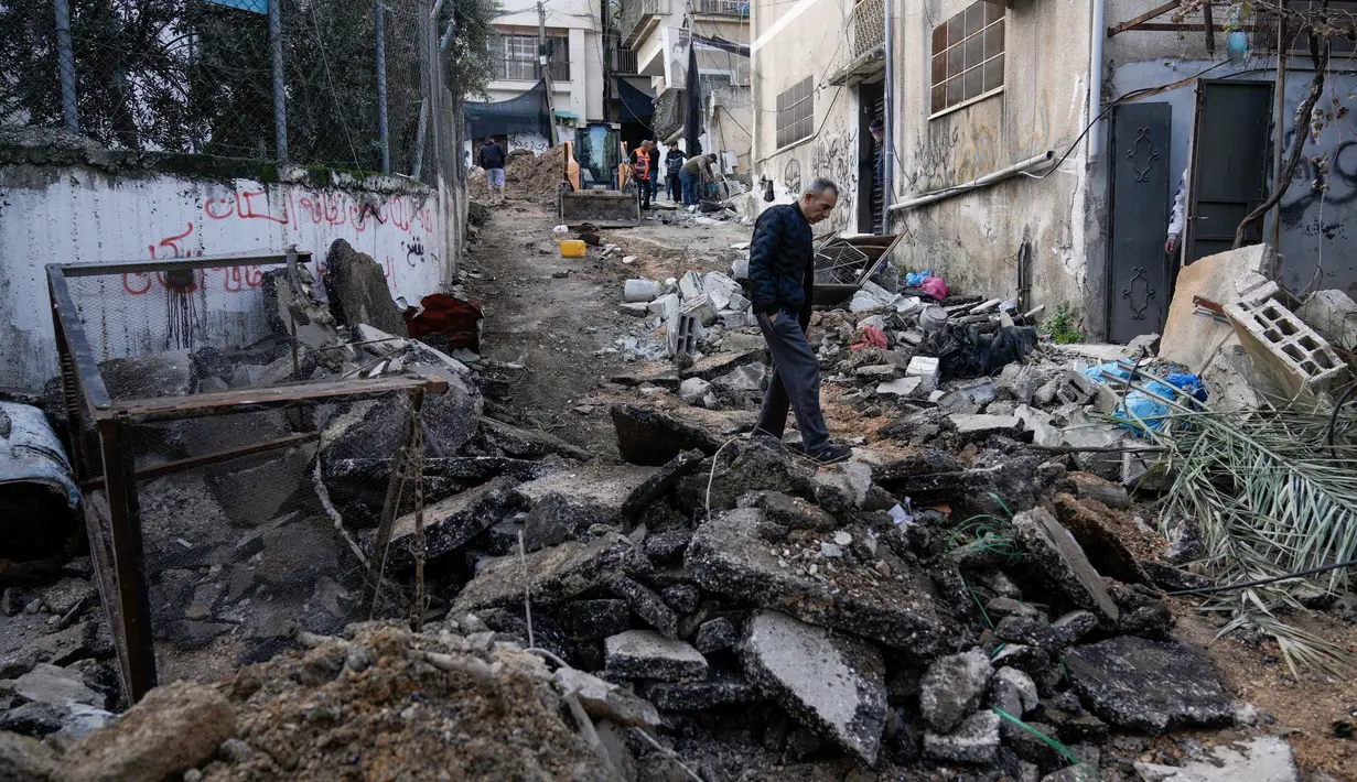 Warga Palestina berjalan setelah penyerbuan militer Israel ke kamp pengungsi Nur Shams di Tepi Barat, Rabu 27 Desember 2023. (AP Photo/Majdi Mohammed)