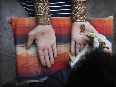 Seorang perempuan mendapatkan desain henna di tangan mereka pada malam festival Karva Chauth di New Delhi, India, Selasa (3/11/2020). Ini adalah festival untuk memulai bulan baru di bulan November di mana para istri akan berpuasa untuk suami-suami mereka. (AP Photo/Manish Swarup)