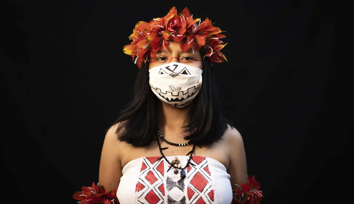 Yusuro Dupohtiro (15) dari kelompok etnis pribumi Dessana dan Sateré Mawé mengenakan pakaian tradisional sukunya dan masker saat pandemi virus corona COVID-19 di Manaus, Brasil, Rabu (27/5/2020). (AP Photo/Felipe Dana)
