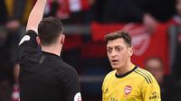 Pemain Arsenal Mesut Ozil (kanan) mendapat kartu kuning dari wasit Chris Kavanagh saat menghadapi Burnley pada pertandingan Liga Inggris di Turf Moor, Burnley, Inggris, Minggu (2/2/2020). Laga berakhir imbang tanpa gol. (Oli SCARFF/AFP)