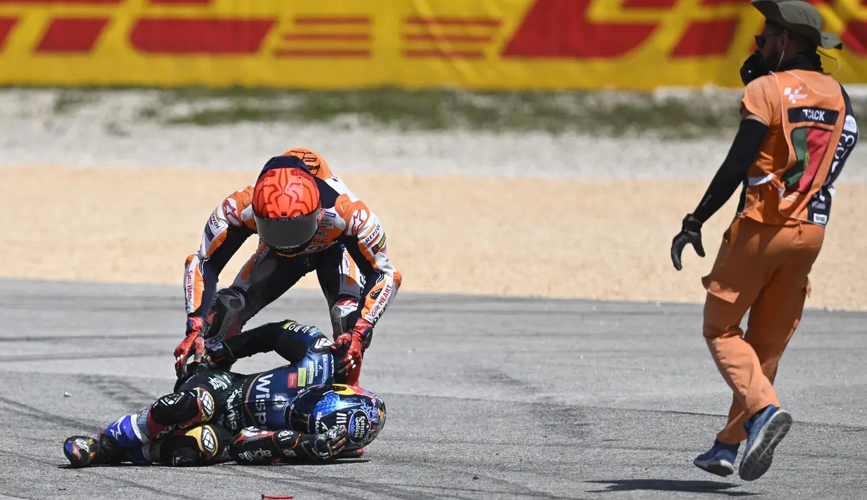 Pebalap Repsol Honda, Marc Marquez (atas) berusaha menolong pebalap CryptoData Aprilia, Miguel Oliveira setelah insiden tabrakan pada balapan MotoGP Portugal 2023 di Sirkuit Internasional Algarve, Portimao, Portugal, Minggu (26/3/2023). (AFP/Patricia De Melo Moreira)