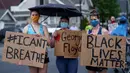 Sejumlah wanita memegang spanduk saat unjuk rasa atas kematian George Floyd oleh polisi di dekat TKP di Minneapolis, Minnesota, Amerika Serikat, Rabu (27/5/2020). Mayoritas demonstran hadir sambil membawa spanduk bertuliskan "I Can't Breathe" dan "Justice 4 Floyd". (Kerem Yucel/AFP)