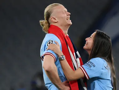 Pemain Manchester City, Erling Haaland, bercanda dengan kekasihnya Isabel Haugseng Johansen saat perayaan gelar juara Liga Champions di Ataturk Olympic Stadium, Istanbul, Minggu (11/6/2023). Erling Haaland tampil luar biasa dan mampu meraih treble winner di musim perdananya bersama City. (AFP/Franck Fife)
