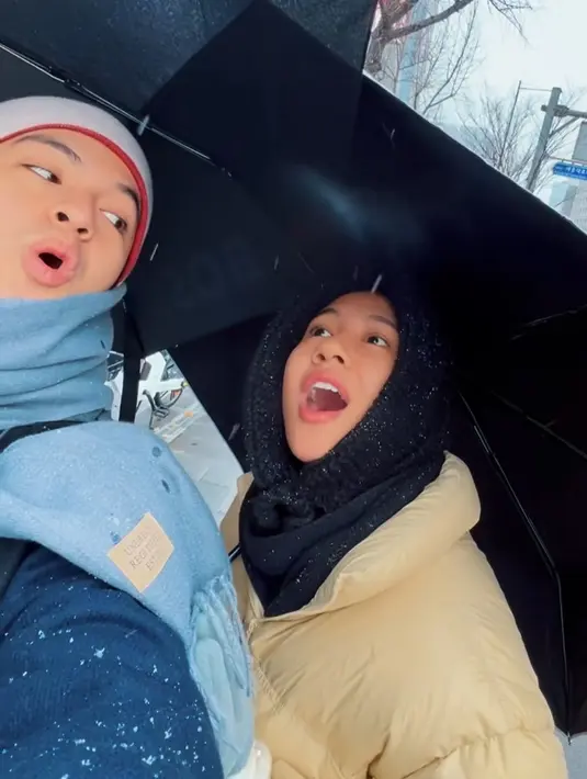 Shenina tampak mengenakan jaket padding warna broken white dipadukan inner hitam dan penutup kepala knit warna senada. [@angga]