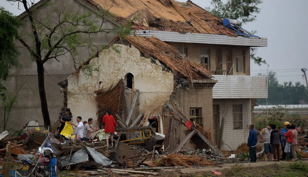 Warga mengamati bangunan rumah yang hancur akibat tornado menyapu wilayah Yancheng, Provinsi Jiangsu, Tiongkok, Kamis (23/6). Cuaca ekstrim termasuk hujan es, hujan lebat, dan angin puting beliung itu menewaskan sedikitnya 51 orang. (JOHANNES EISELE/AFP)