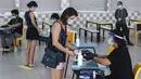 Pemilih mengenakan masker saat memverifikasi identitas dengan petugas pemilu di TPS Sekolah Tinggi Chung Cheng, Singapura, Jumat (10/7/2020). Pemilu di tengah pandemi COVID-19, warga Singapura memberikan suara mereka dengan mengenakan masker dan sarung tangan plastik. (AP Photo)