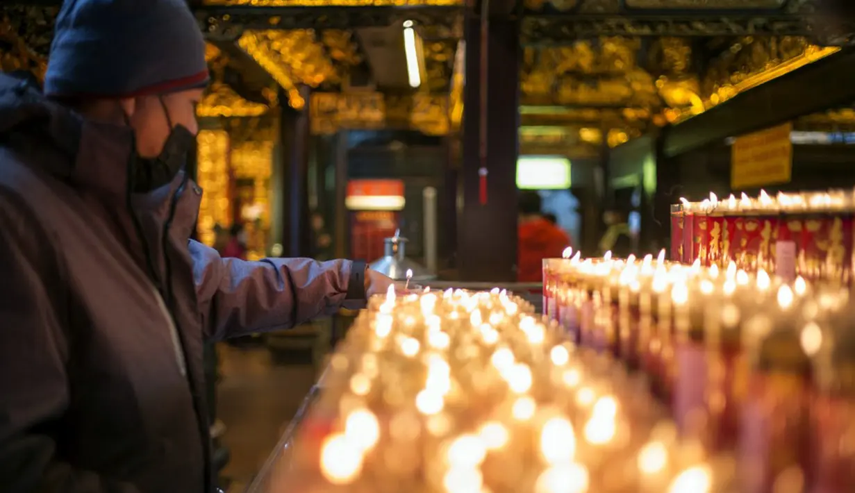Seorang pria meletakkan lilin saat dia berdoa untuk keberuntungan di Kuil Hongludi Nanshan Fude untuk menandai hari ketiga Tahun Baru Imlek di New Taipei City, Taiwan, Selasa (24/1/2023). (Sam Yeh/AFP)