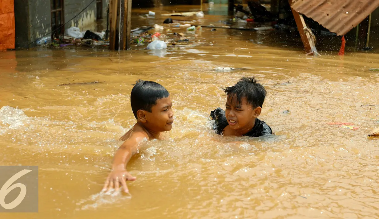 Anak-anak bermain di lokasi banjir yang merendam kawasan Kampung Pulo, Jakarta, Rabu (25/11). Air aliran kali Ciliwung mulai memasuki rumah warga sekitar pukul 03.00 Wib dini hari tadi. (Liputan6.com/Yoppy Renato)