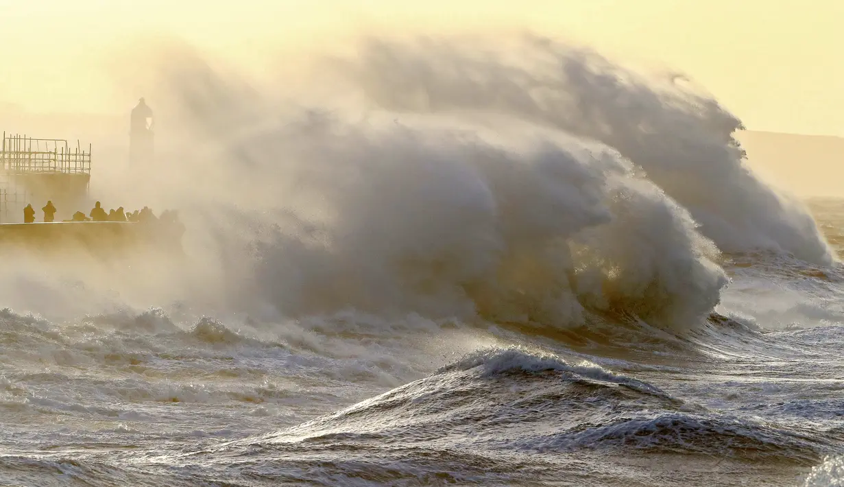 Ombak menghantam tembok laut saat Badai Eunice membawa angin kencang di Porthcawl, Wales, Inggris (18/2/2022). Inggris menempatkan tentara dalam keadaan siaga dan sekolah-sekolah ditutup ketika prakiraan cuaca mengeluarkan dua peringatan "cuaca merah". (AFP/Geoff Caddick)