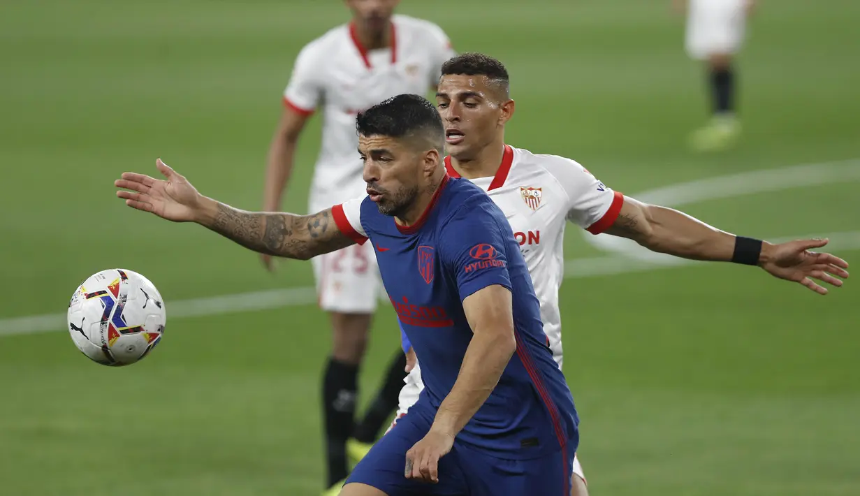 Striker Atletico Madrid, Luis Suarez, berebut bola dengan pemain Sevilla, Diego Carlos, pada laga Liga Spanyol di Stadion Ramon Sanchez-Pizjuan, Minggu (4/4/2021). Sevilla menang dengan skor 1-0. (AP Photo/Angel Fernandez)