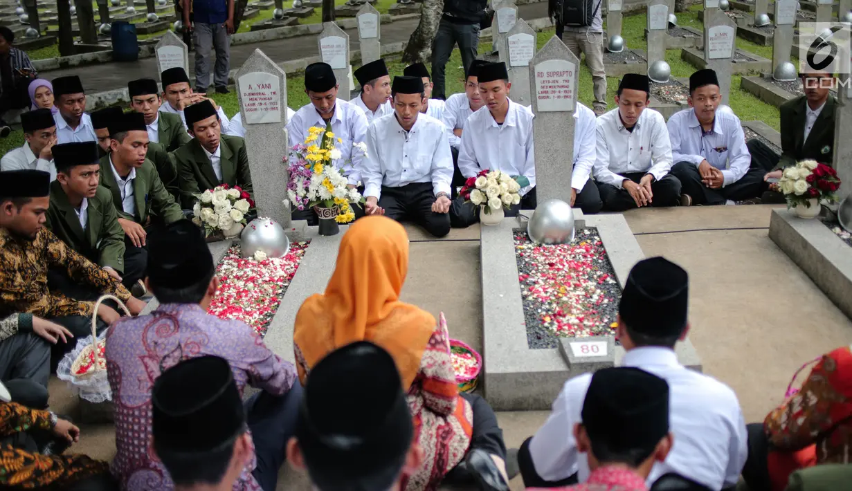 Menteri Sosial Khofifah Indar Parawansa bersama para santri penghafal Alquran berdoa bersama di salah satu makam pahlawan saat melakukan ziarah di Taman Makam Pahlawan Kalibata, Jakarta, Senin (2/10). (Liputan6.com/Faizal Fanani)