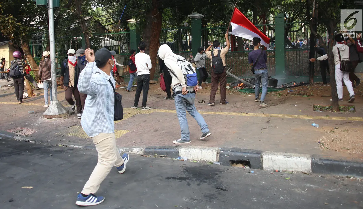 Pelajar melempari Gedung DPR dengan batu saat berunjuk rasa di Palmerah, Jakarta, Rabu (25/9/2019). Pihak kepolisian menembakan gas air mata untuk memukul mundur pelajar. (Liputan6.com/Angga Yuniar)