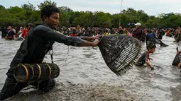 Penduduk desa menangkap ikan selama upacara penangkapan ikan tahunan di komune Choam Krovean di provinsi Tboung Khmum pada 18 Februari 2023. Dengan menggunakan keranjang bambu buatan tangan dan jaring nilon, ratusan orang mengarungi danau berlumpur setinggi paha di Kamboja timur pada hari Sabtu untuk upacara penangkapan ikan tahunan, di mana hanya alat-alat tradisional yang digunakan. (AFP/Tang Chhin Sotthy)