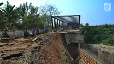 Pengendara roda dua melintasi jalan longsornya tepian jembatan Cipamingkis Cibarusah, Kab Bekasi, Jawa Barat (15/7). Sudah lebih empat bulan jembatan tersebut tertutup bagi kendaraan roda empat. (Merdeka.com/Arie Basuki)