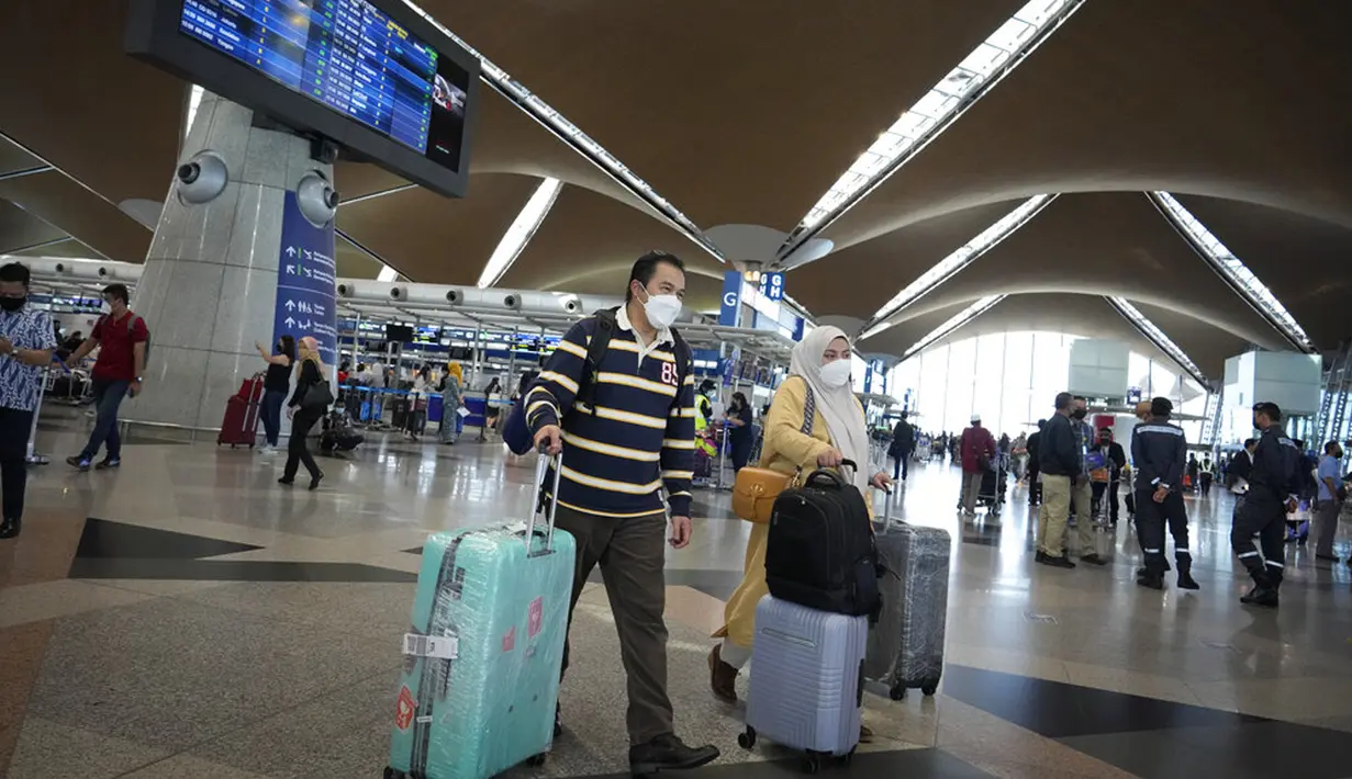 Pelancong berjalan untuk check-in di Bandara Internasional Kuala Lumpur, Sepang, Malaysia, Jumat (1/4/2022). Mulai hari ini, Malaysia membuka perbatasannya untuk orang asing dan pelancong yang sudah divaksin COVID-19 lengkap tanpa harus menjalani karantina. (AP Photo/Vincent Thian)