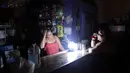 Dua orang wanita berbincang di sebuah kedai kopi selama pemadaman listrik di San Juan, Puerto Rico, Rabu (21/9). Kebakaran yang terjadi di pembangkit listrik Puerto Rico menyebabkan 1,5 juta penduduk pulau itu hidup tanpa listrik. (REUTERS/Alvin Baez)